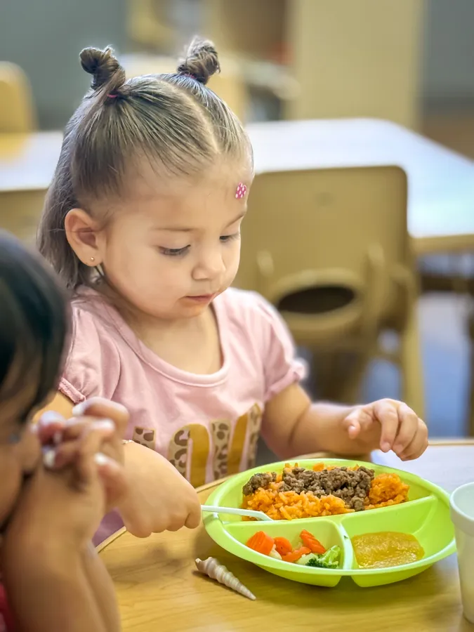Child enjoying a healthy meal at First Chapter Academy
